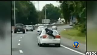 Man Rides On Trunk Of Car In The Middle Of The Highway