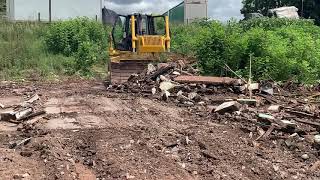 Dozer KOMATSU D65 pushing rubble from demolished house