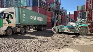 Container reach stacker unloading container in muddy conditions with pot holes